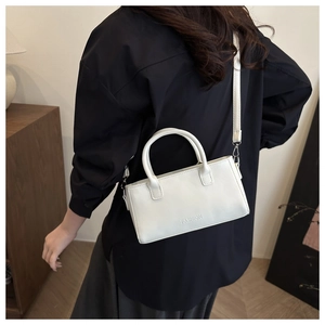 Sac à main blanc en cuir avec poignées rondes et bandoulière porté par un mannequin