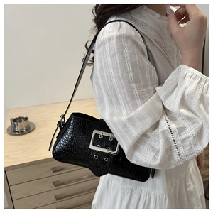 Detail of glossy black crocodile pattern shoulder bag with oversized silver metal buckle