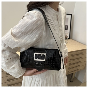 Detail of black crocodile embossed shoulder bag with silver buckle and glossy finish