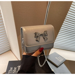 Detail of silver metallic mini bag with 3D metal bow and elegant chain strap
