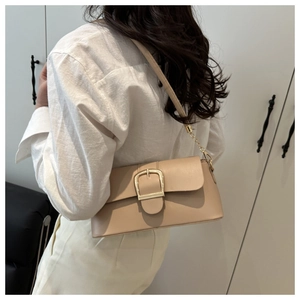 Dettaglio borsa a spalla beige minimalista con fibbia dorata e tracolla a catena