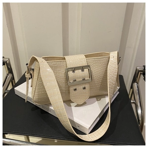 Detail of cream crocodile embossed baguette bag with silver buckle on a vintage book
