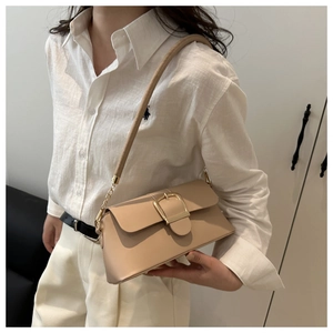 Dettaglio della borsa beige con fibbia dorata e tracolla in catena su una modella