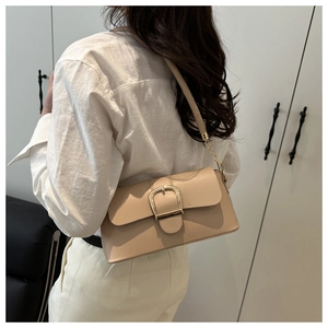 Dettaglio della borsa a tracolla in pelle beige con fibbia dorata e catena metallica