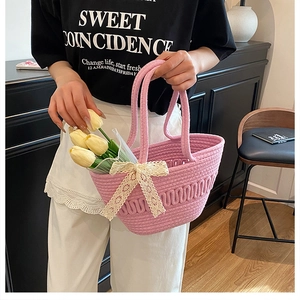 Detailed texture of pink woven bucket bag featuring delicate white lace bow decoration