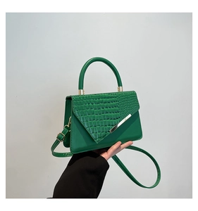 Detail of green faux crocodile texture and gold V-shaped trim on a chic lady's handbag
