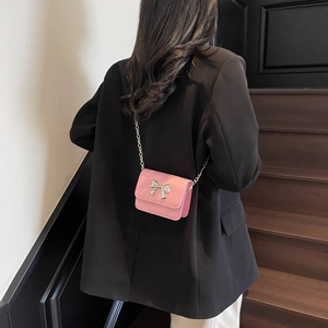 Pink crossbody square bag with silver metal bow and chain strap on a model