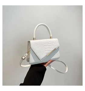 Detail of white crossbody bag with crocodile embossed flap and golden metal accents