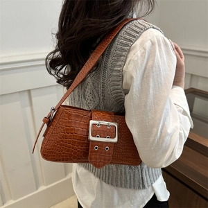 Vintage brown crocodile pattern shoulder bag with silver buckle worn by a model