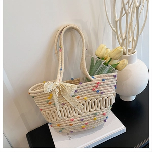 Detail of woven straw bucket bag featuring colorful dots and a lace bow tie accessory