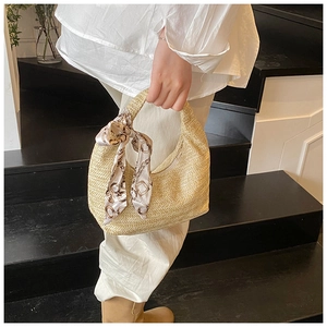 Détail du sac demi-lune tressé avec foulard en soie à motif chaîne sur l'anse