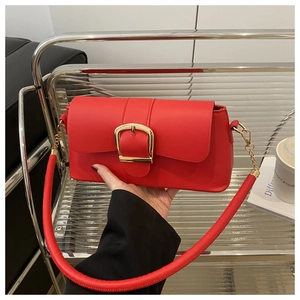 Dettaglio borsa in pelle rossa con grande fibbia dorata e manico tubolare