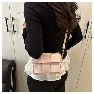 Detail of light pink woven shoulder bag with glossy texture and silver metal hardware