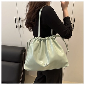Détail du sac cabas plissé vert menthe en cuir verni brillant avec un nœud argenté