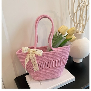 Detailed close-up of pink woven cotton bucket bag with delicate white lace bow detail
