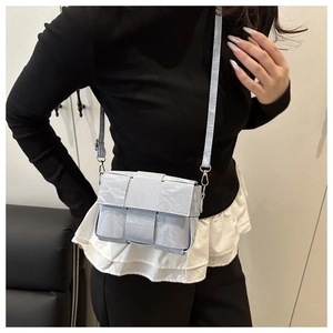 Close-up of light blue woven crossbody bag showing intricate texture and silver hooks