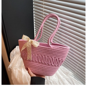 Detail of pink woven straw bucket bag with delicate cream lace bow accent
