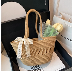 Close-up of straw bucket bag featuring a cream lace bow and decorative tulip flowers
