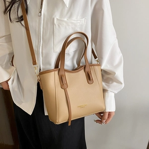 Borsa tote minimalista in pelle beige con manici marroni indossata da una modella