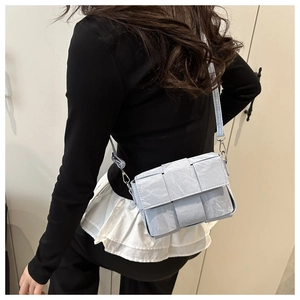 Detail of light blue woven texture shoulder bag with wide weave and silver metal hardware