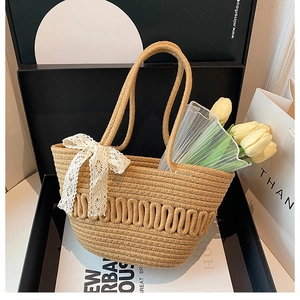 Detailed weave pattern of a straw bucket bag with white lace bow and tulips in a gift box