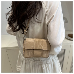 Macro view of beige woven square bag showing unique crinkled paper texture and flap detail