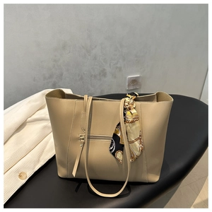 Detail of khaki tote bag with zipper pocket, leather tassel, and retro silk scarf wrap