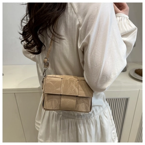 Detail of light beige woven crossbody bag with crinkled paper texture and thin strap