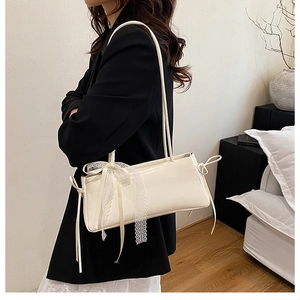 Detalle de bolso de hombro blanco con elegante lazo de encaje y un acabado brillante liso