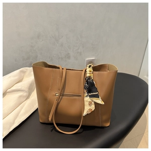 Detail of a large brown tote bag with decorative silk scarf and functional back zipper