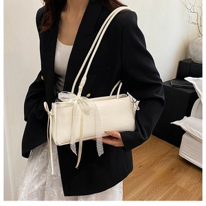 Detalle de elegante bolso de cuero PU blanco con delicado lazo de encaje y correa fina