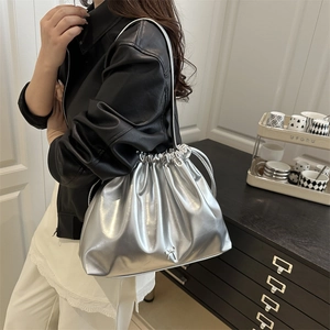 Metallic silver pleated drawstring shoulder bag with a bow detail on a stylish model