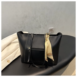 Detail of black tote bag featuring white stitching, fringe zipper, and yellow silk scarf