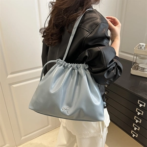 Light blue pleated bucket bag with a silver bow accent and drawstring closure