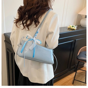 Detail of light blue faux leather shoulder bag with decorative lace ribbon bow