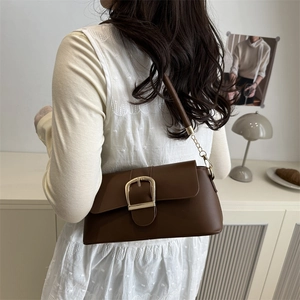 Vintage brown faux leather underarm bag with gold buckle and chain strap shown in a room