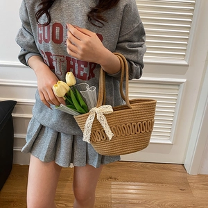 French style straw bucket bag with white lace bow and yellow tulips inside for spring