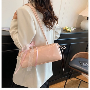 Detalle de un bolso de hombro rosa con lazos de encaje y diseño lateral fruncido