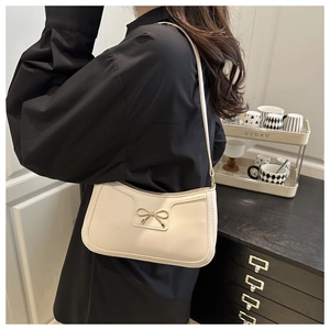 Detail of off-white PU leather shoulder bag with golden metal bow buckle and stitching