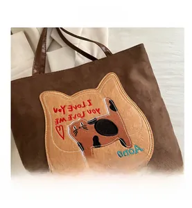 Detail of dark brown tote bag featuring a cute cat profile patch and embroidered text