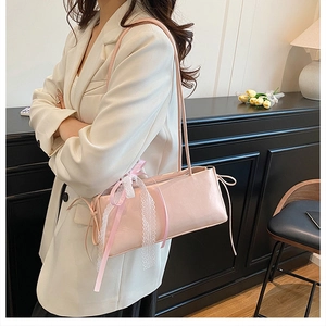 Detail of pink shoulder bag with lace bow and ribbon decoration on a white blazer