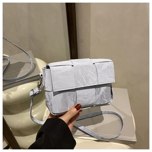 Close-up of light blue woven leather bag with marble texture and silver buckle