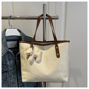 Dettaglio della borsa tote crema con trame geometriche e tracolla marrone a contrasto