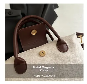 Close-up of premium magnetic metal closure on white pebbled leather tote bag