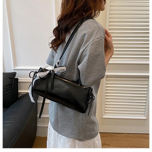 Detalle de bolso negro estilo balletcore con ribete de encaje blanco y lazo decorativo