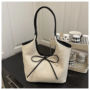 Detail of woven straw bucket bag with black leather bow and handle for women