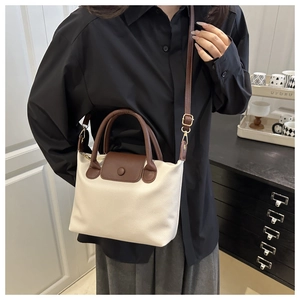 Detail of cream pillow bag with brown leather trim and golden metal hardware