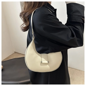 Detailansicht der cremefarbenen Halbmond-Tasche mit Metallverschluss an einem Modell
