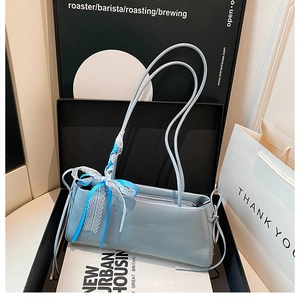Detalle del bolso de hombro de charol azul claro con lazo de encaje y cinta de seda decorativa