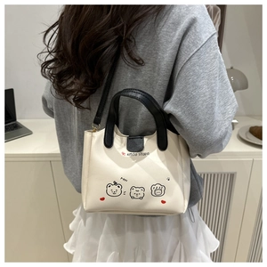 Détail du sac à bandoulière mignon avec poignées contrastées porté par le modèle